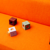 AVOLT Square 2 - Collection of six power extensions in muted tones on a wood table.
