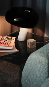 AVOLT Square 1 (CH) USB-C cube on glass side table beside marble lamp and stacked books