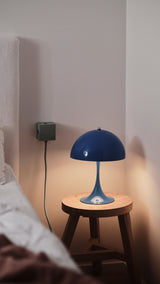 AVOLT Square 1 USB-C wall cube mounted beside bed, green charger and cable powering a blue bedside lamp