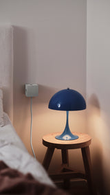 lifestyle: AVOLT Square 1 USB-C wall charger mounted beside a blue bedside lamp on a wooden stool